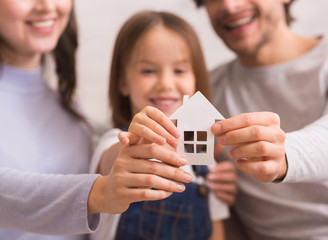 Cutout Paper House In Hands Of Happy Family Of Three