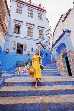 Colorful Traveling By Morocco. Young Woman In Yellow Dress Walking In  Medina Of  Blue City Chefchaouen.