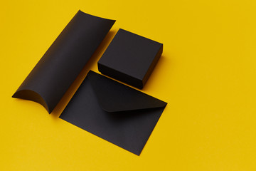 Obraz premium Mock up of two black paper present boxes and an envelope on the yellow background. Presentation template