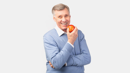 Cheerful Senior Gentleman Holding Apple Posing Over Gray Background, Panorama