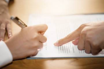 The hand of a business man is using the index finger to let the customer sign the contract, contract, business agreement.
