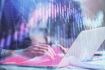 Double exposure of market chart with man working on computer on background. Concept of financial analysis.