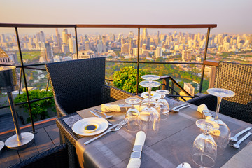 Table setting on roof top restaurant with megapolis view, Bangkok Thailand.