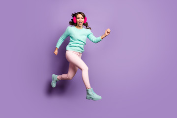 Fototapeta na wymiar Full length photo of funky lady jumping high up excited good mood rushing sale sopping center wear fuzzy pullover pastel pink ear muffs pants shoes isolated purple color background