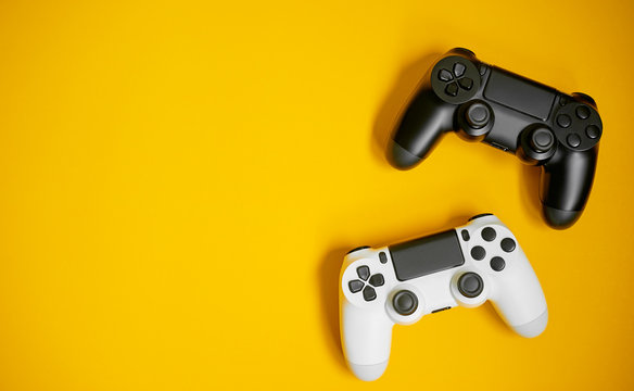 Computer game competition. Gaming concept. White and black joysticks on yellow background.