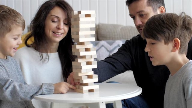 Slow motion of wooden tower is crumbling while family playing game together