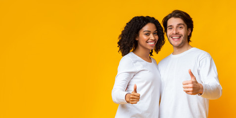 Positive interracial couple showing thumbs up, approving something