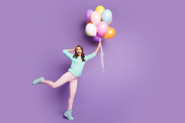 Fototapeta na wymiar Full size photo of surprised feminine girl get present many baloons flying sky she catch impressed scream wow omg wear pink pants trousers pastel turquoise jumper isolated purple color background