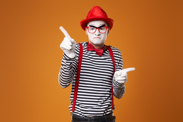 Seriouse mime in red hat and vest on orange background