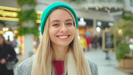 Portrait face young beautiful woman wear green hat look at camera smile happy fashion Christmas holidays attractive winter model person casual close up slow motion