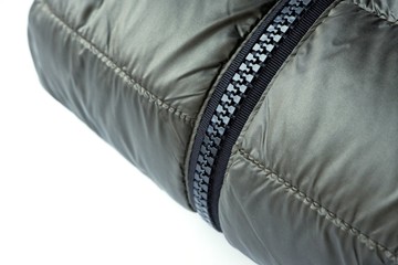 Close-up zipper closure on a light warm olive-colored jacket. Warm clothes, accessories for outerwear.