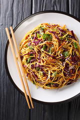 Vegetarian Asian egg noodle salad with seasonal vegetables close-up in a plate. Vertical top view