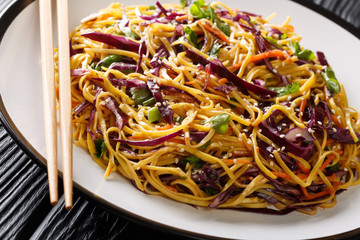 Tasty egg noodles with vegetables and sesame seeds close-up in a plate. horizontal