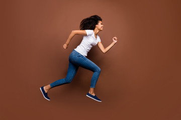 Fototapeta na wymiar Full body profile photo of crazy funny dark skin lady jumping high sportive competitions participant rushing finish wear white t-shirt jeans isolated brown color background