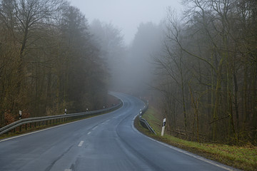 Kurvige Stra&szlig;e im Wald bei Nebel