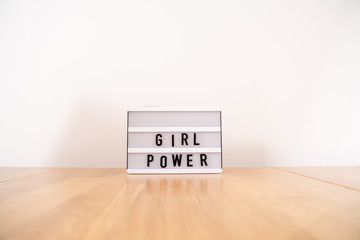 Girl power text on the lightbox. Side view on wooden table. Gender equality