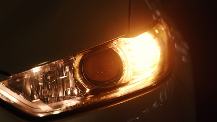 Car detail. Modern new white car tail lights shining red close-up. Rear back lights of sports luxury car flashing in the dark at open parking space.