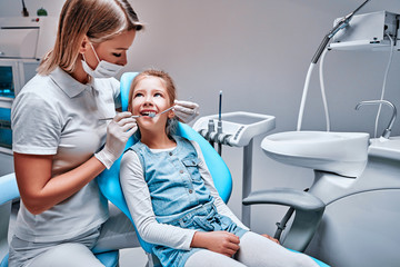 Obraz premium Happy female dentist with patient girl at clinic