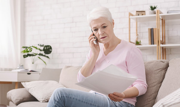 Shocked retired woman listening to bank agent with documents