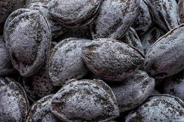 Unpeeled roasted apricot kernels, in a round wooden bowl