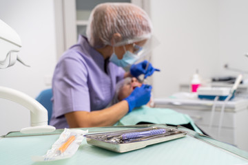 in the foreground is the focus of dental instruments, in the background is out of focus the dentist is treating the patient.