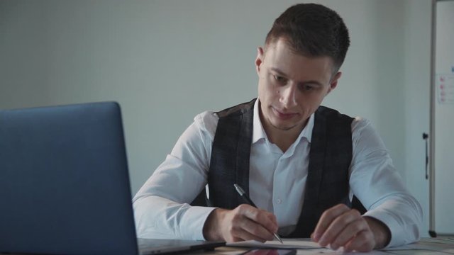 Concept of creating new website page. Qualified, intelligent adult person in formal wear clothes working inside modern work space office with bright interior. Man sitting behing table and using laptop