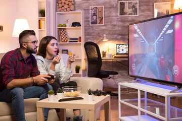 Boyfriend playing video games on television using controller