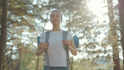 Woman young tourist with backpack walking in the fall forest on sunny summer day smile look around vacation camping hiking travel wood hike active journey young nature activity slow motion