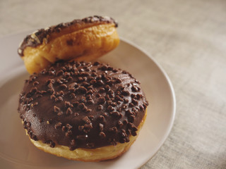 Two taste chocolate round doughnut on a white plate. Bakery product. Selective focus.