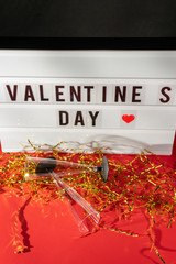 Bright Valentine's Day sign, champagne glasses and gold confetti.