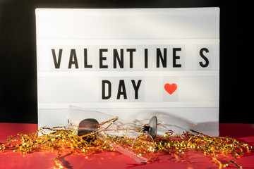 Bright Valentine's Day sign, champagne glasses and gold confetti.
