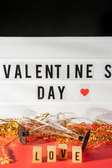 Bright Valentine's Day sign, champagne glasses and gold confetti.