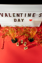 Bright Valentine's Day sign, champagne glasses and gold confetti.