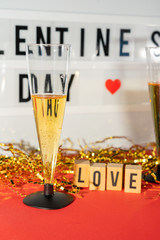 Bright Valentine's Day sign, champagne glasses and gold confetti.