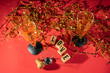 Bright Valentine's Day sign, champagne glasses and gold confetti.