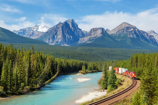 Freight train moving along Bow river in Rocky Mountains range, Canada