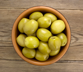  Green olives  in bowl on wooden table