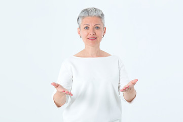 Adult woman, mother holds her hands at chest level as a symbol of love and hug. Portrait of a mature woman with a short haircut and gray hair. Beautiful female on light background and copy space.