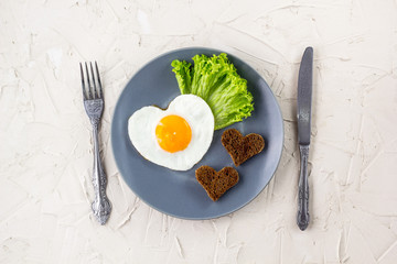 Valentines day breakfast with heart shaped fried eggs served on grey plate