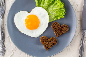 Valentines day breakfast with heart shaped fried eggs served on grey plate