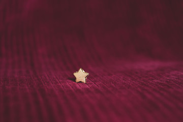 kleiner goldener Stern auf edlem weinroten Stoff aus Samt; Hintergrund und Copyspace