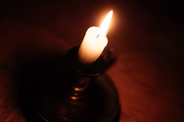 Nahaufnahme einer Flamme einer Kerze in einem Kerzenständer aus Messing im dunkeln