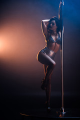 sexy stripper in undrewear dancing striptease near pylon on blue and orange