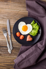Valentines day breakfast with heart shaped fried eggs served on grey plate.