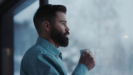 Close up handsome businessman drinking coffee and admire view standing by window in office attractive boss enjoying tea looking young break manager executive observing relaxation view slow motion