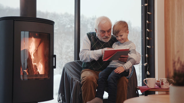 Close Up Grandfather And Grandson Using Digital Tablet For Surfing Internet And Playing Game Near The Fireplace At Home Grandpa Adult Grandchild Child Childhood Communication Computer Slow Motion