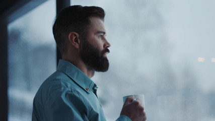 Close up handsome businessman drinking coffee and admire view standing by window in office...