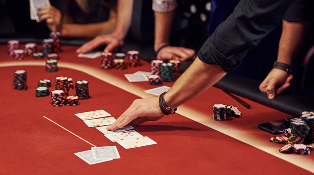 Close up view of elegant young people's hands that playing poker in casino