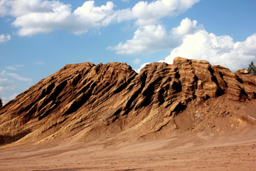 The waste heaps landscape similar to canyon after coal heaps are extracted. Consequences of opencast coal mining. Terricone against a background of blue sky with white clouds