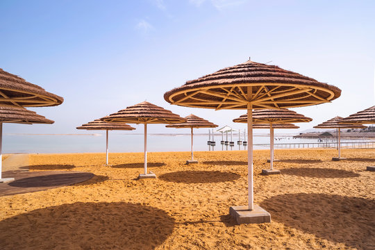straw umbrellas from sun on the sandy shore of the dead sea in Ein Bokek. Israel. A beautiful place for rest and treatment.